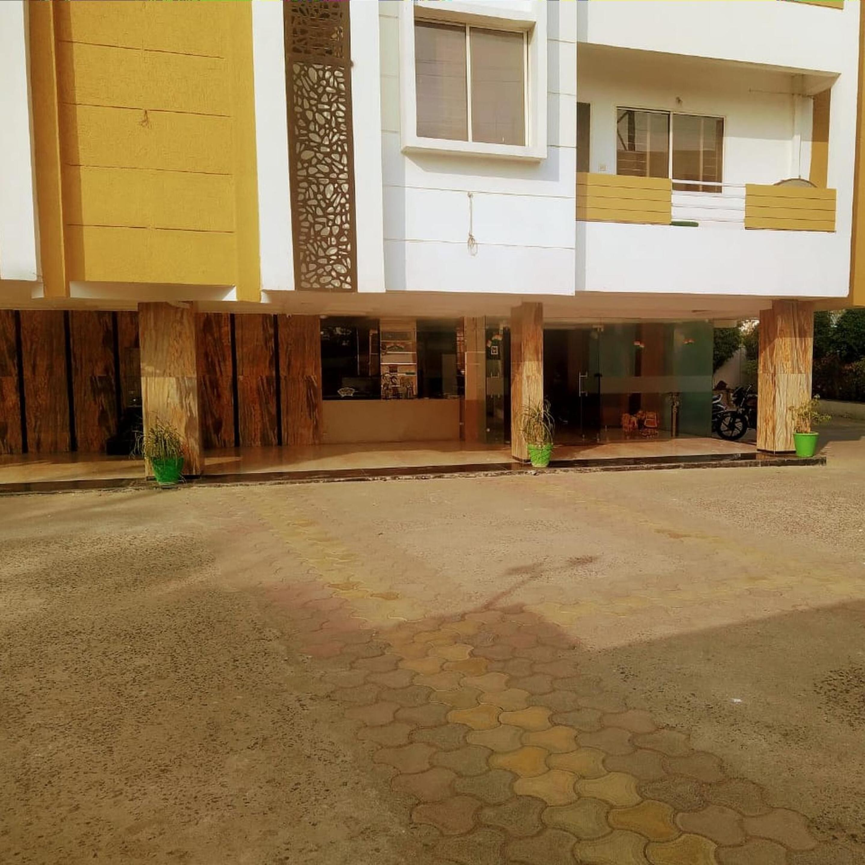 A modern building with a flat roof, large windows, and a paved entrance area.