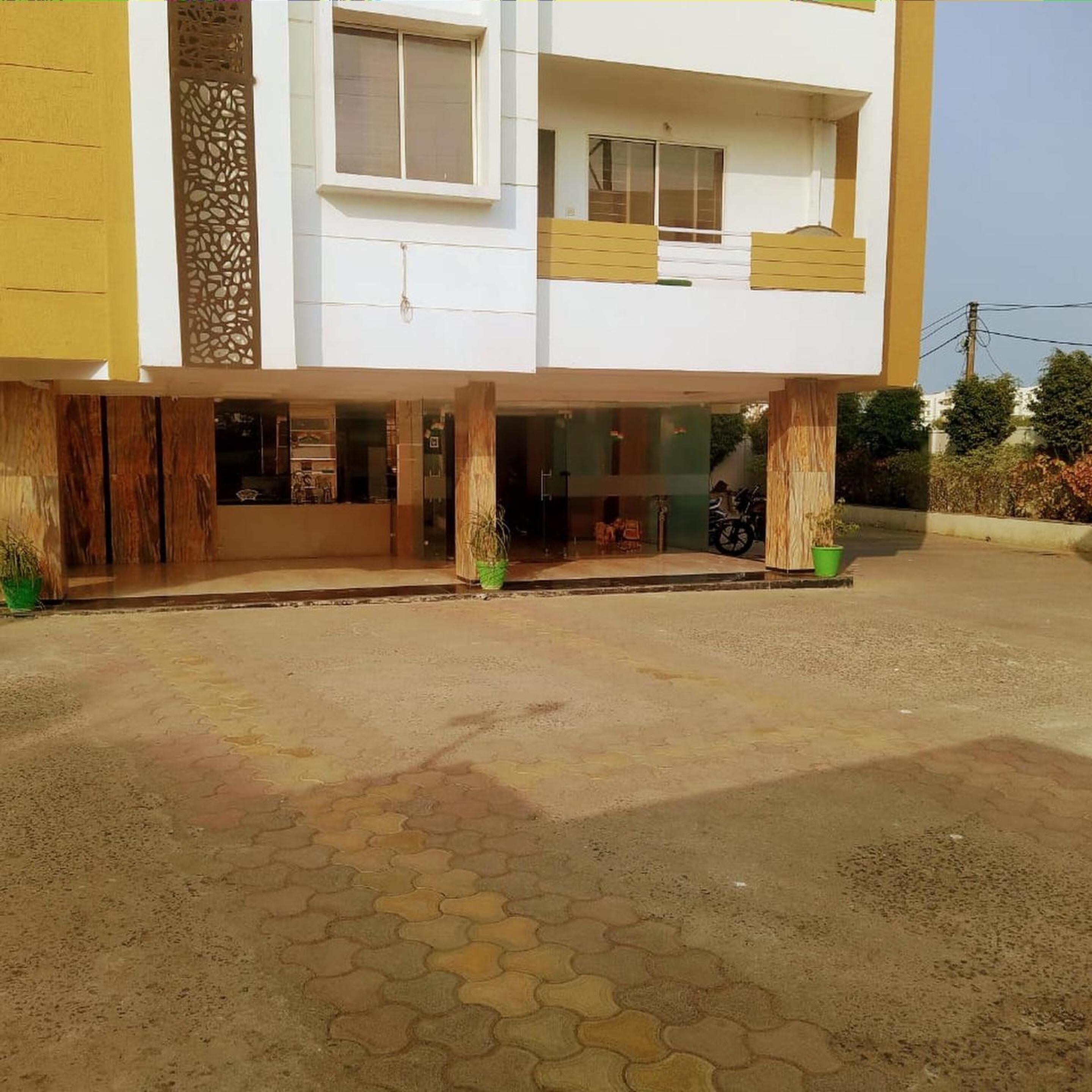 A two-story building with a flat roof, large windows, and a paved entrance area with hexagonal tiles.