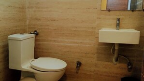 A small bathroom with a toilet, sink, and a wooden floor.