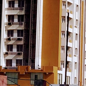 A multi-story building with balconies, a central stairwell, and a yellow facade.