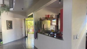 A modern kitchen with a built-in stove, a refrigerator, and a window overlooking a garden. - Beach House in Porto Seguro (Coroa Vermelha) 30 meters from the beach.  (BA)