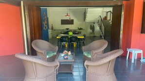 A dining area with wicker furniture and a table with a vase of flowers. - Beach House in Porto Seguro (Coroa Vermelha) 30 meters from the beach.  (BA)