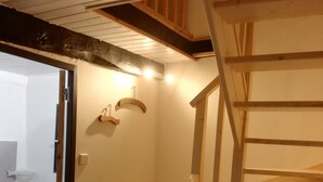 Eine Holztreppe mit Geländer, eine kleine Ablage mit zwei Haken und ein Korb auf einer Theke.
