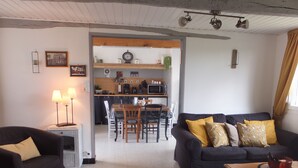 Ein Wohnzimmer mit einem dunklen Sofa, einem Couchtisch und einem Essbereich mit Tisch und Stühlen.