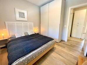 Makuuhuoneessa on sänky, yöpöydällä lamput, vaatekaappi ja seinällä kehystetty taulu.