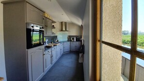 A modern kitchen with a built-in oven, a stovetop, and a range hood. There is a window providing a view of the outdoors.