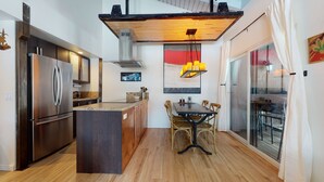 A modern kitchen with a built-in island, stainless steel appliances, and a dining area with a table and chairs. - Mammoth Estates Studio Condos - 2 Blocks from The Village Gondola Station by RedAwning (Mammoth Lakes)