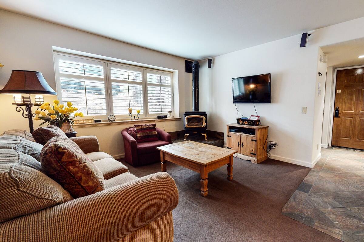 A living room with a sofa, armchair, table, and a fireplace.