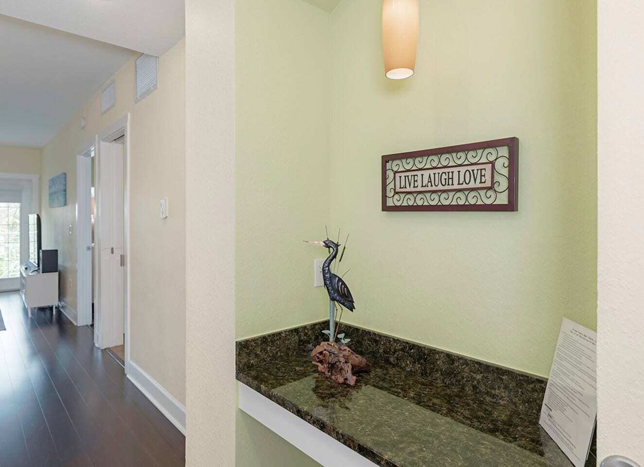 A reception area with a 'Live Laugh Love' sign, a decorative bird sculpture, and a reception desk.
