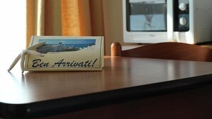 Une carte sur laquelle on peut lire « Ben Arrivati ! » est posée sur une table, à côté d’un téléviseur blanc.