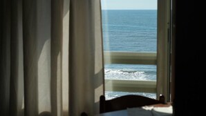 A room with a view of the ocean through a window with curtains. - Two-room apartment, beachfront, floor 2 (Sunflower) (Anzio)