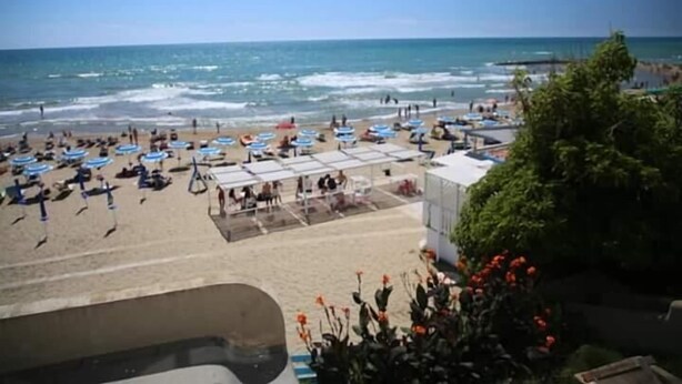 A beach with umbrellas and people, a clear sky, and a view of the ocean. - Studio apartment, beachfront, floor 2, private descent to the beach (Narcissus) (Anzio)