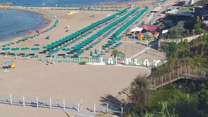 A beach with rows of green umbrellas and beach chairs, a pier, and a view of the sea. - Studio apartment, beachfront, floor 2, private descent to the beach (Narcissus) (Anzio)