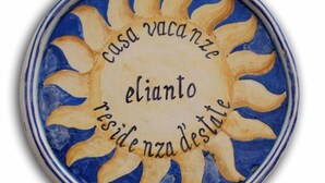 A circular ceramic plate with a sun design and text in Italian. - Studio apartment, beachfront, floor 2, private descent to the beach (Narcissus) (Anzio)