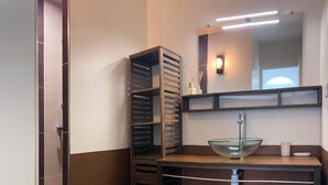 Une salle de bain avec un lavabo en verre, un miroir et un porte-serviettes.