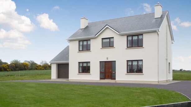 A two-story house with a grey roof, a front door, and a garage. - Boherbue Holiday Home (Boherboy)
