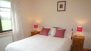 A neatly made bed with white bedding and two red lamps on wooden nightstands. - Boherbue Holiday Home (Boherboy)