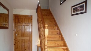 A wooden staircase with a handrail, a wooden door, and a framed picture on the wall. - Boherbue Holiday Home (Boherboy)