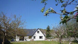 Ein Haus mit geneigtem Dach, einem sichtbaren Fenster und einer Rasenfläche im Vordergrund.