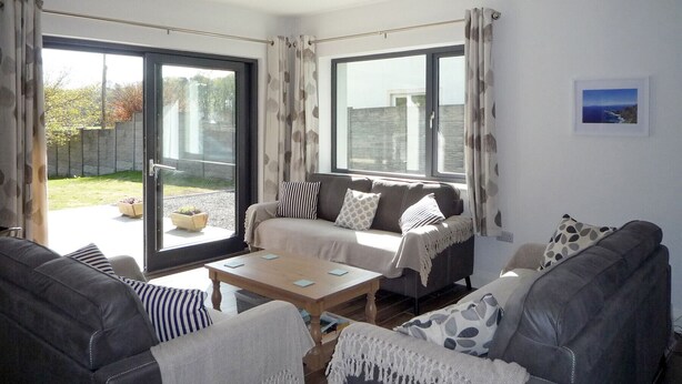 Ein Wohnzimmer mit zwei Sofas, einem Couchtisch und Blick ins Freie durch große Fenster.
