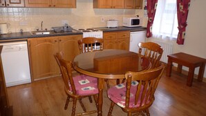 A kitchen with wooden cabinets, a stove, a microwave, and a dining table with chairs. - Lakeside Lodge Bantry (Bantry)