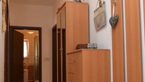 Un passadís amb armaris de fusta, una cistella de vimet i una decoració penjada a la paret amb forma de cor.