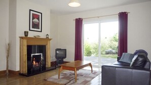 Un salon avec une cheminée, un t éléviseur, un canapé et une vue sur l’extérieur.