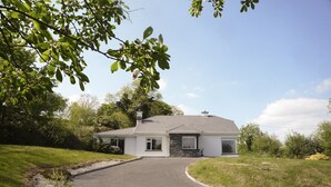 Une maison moderne à deux étages, dotée d’une façade en pierre, d’une allée sinueuse et d’une pelouse bien entretenue.