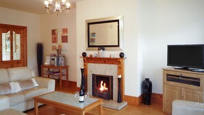 Ein Wohnzimmer mit Kamin, Fernseher und einer Couch.