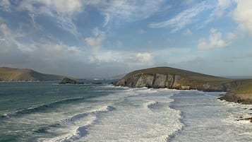 A coastal landscape with rocky cliffs and waves crashing onto the shore.
