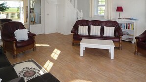 A living room with a leather sofa, a white coffee table, and a bookshelf. - The White Cottage Leap (Reenascreena)