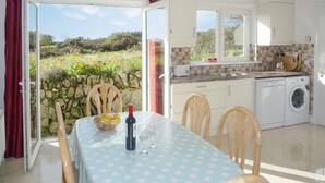 A dining area with a table set for two, a bottle of wine, and a bowl of fruit. - The White Cottage Leap (Reenascreena)