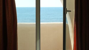 A view of the ocean through a window with curtains.