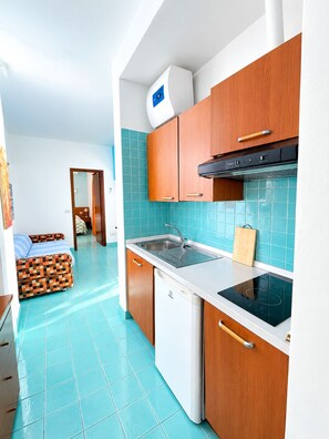 A compact kitchen with a dishwasher, stove, and a sink. - Two-bedroom apartment, large terrace, ocean view, 1st floor (Pink) (Anzio)