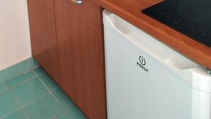 Una cocina compacta con armarios de madera, un lavamanos de acero inoxidable y un lavavajillas blanco.
