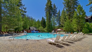 A pool area with lounge chairs, a pool, and a building in a forested setting. - Chamberlands Cabin: 5  BR, 3  BA House in Tahoma, Sleeps 10 (Tahoma)