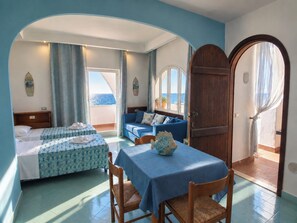 Une chambre d’hôtel avec deux lits, une table à manger et vue sur la mer.