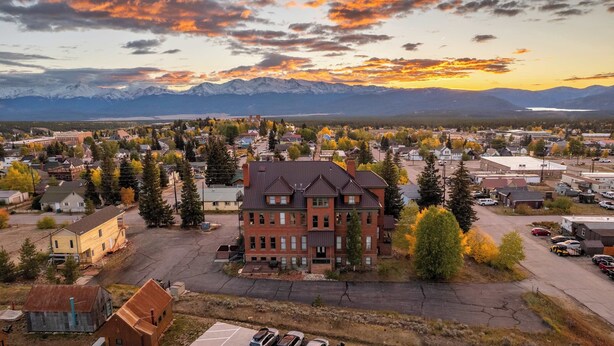 A residential area with a prominent red brick building, surrounded by trees and a mountainous backdrop. - Papa's Place — Historic 1BR Brick Unit, Walk to Main St Leadville (Leadville)
