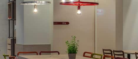 A modern dining area with a long table, colorful chairs, and unique circular pendant lights.