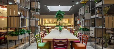 Un comedor amplio con una mesa larga, numerosas sillas y estantes con plantas.