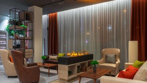 A modern living room with a fireplace, comfortable seating, and a bookshelf. - IntercityHotel Budapest (Budapest)