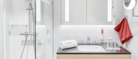 A modern bathroom with a glass-enclosed shower, a wooden vanity with a black metal frame, a white sink, and a red towel hanging on the wall.