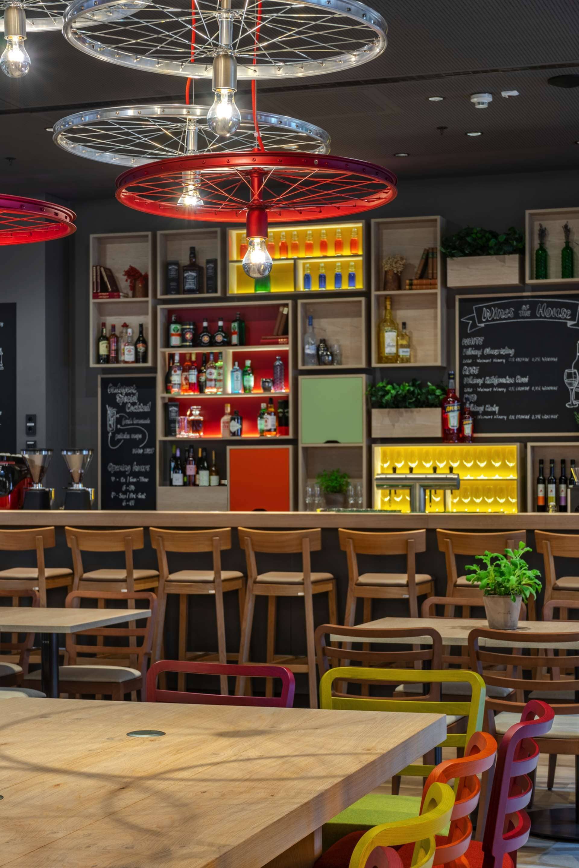 A bar area with wooden furniture, shelves with bottles, and a chalkboard menu.