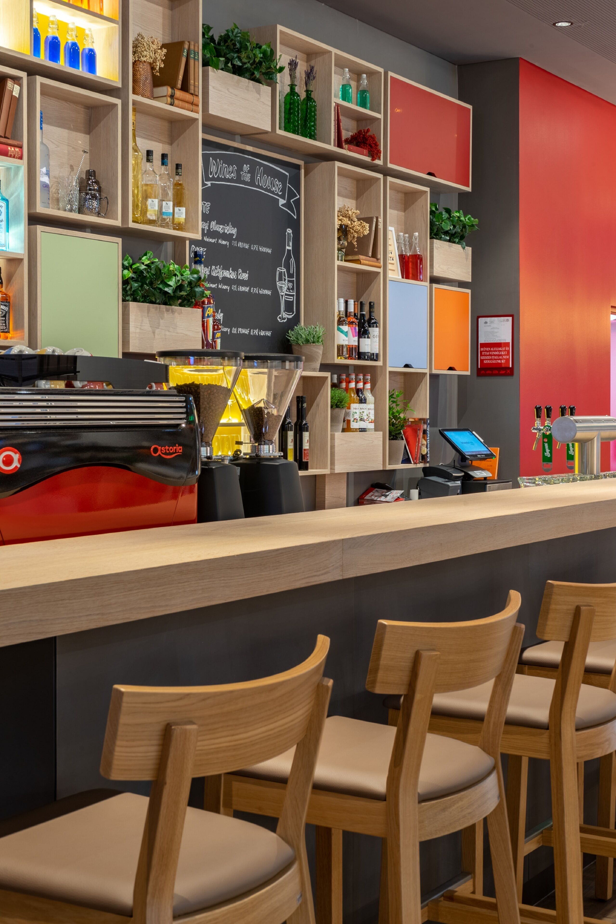 A bar area with wooden shelves, chairs, and a coffee machine.