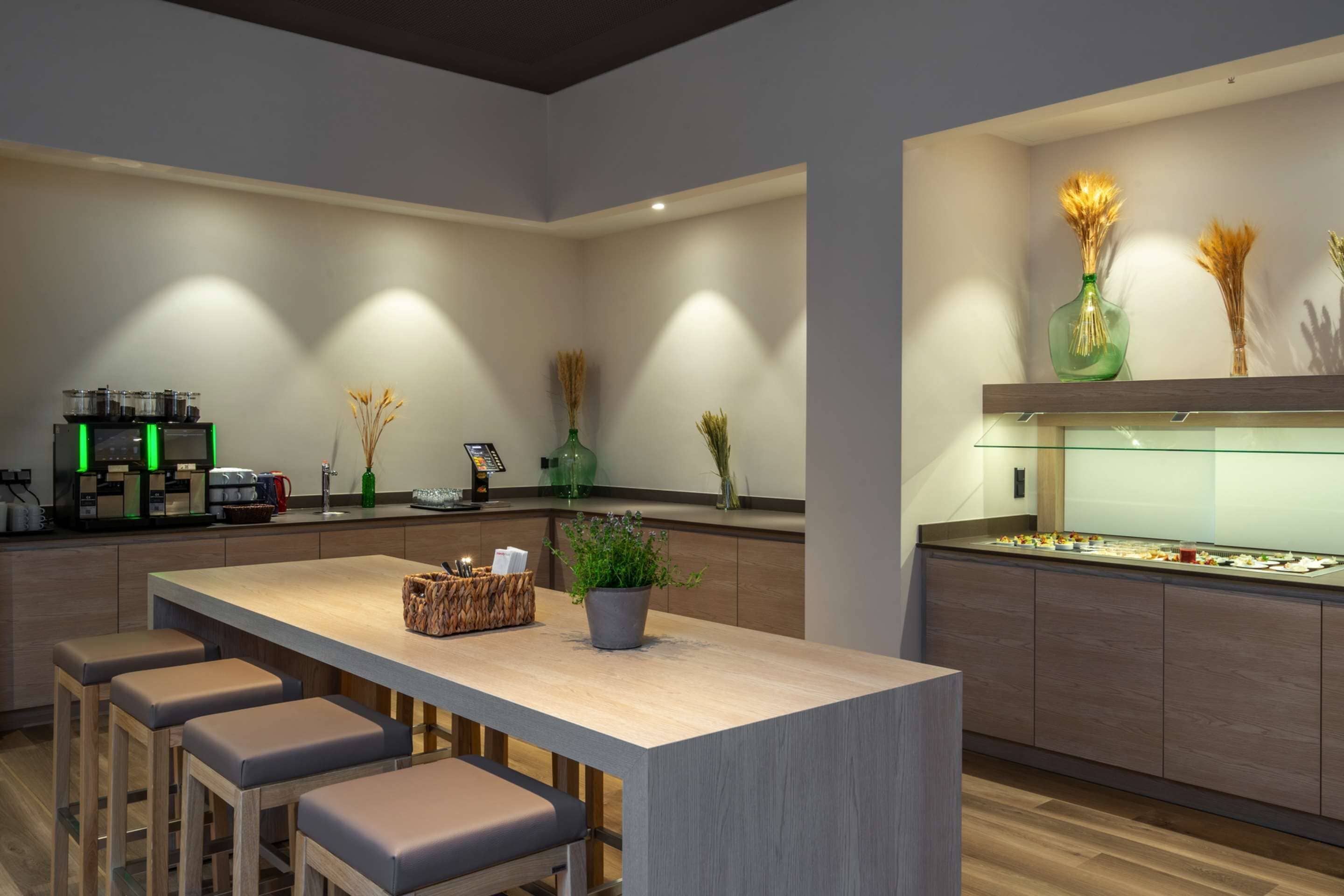 A modern kitchen with a central island, bar stools, and a display case.