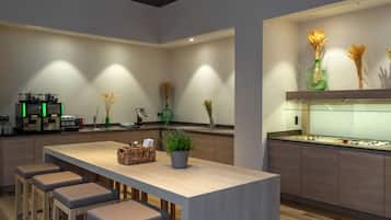 A modern kitchen with a central island, bar stools, and a display case.
