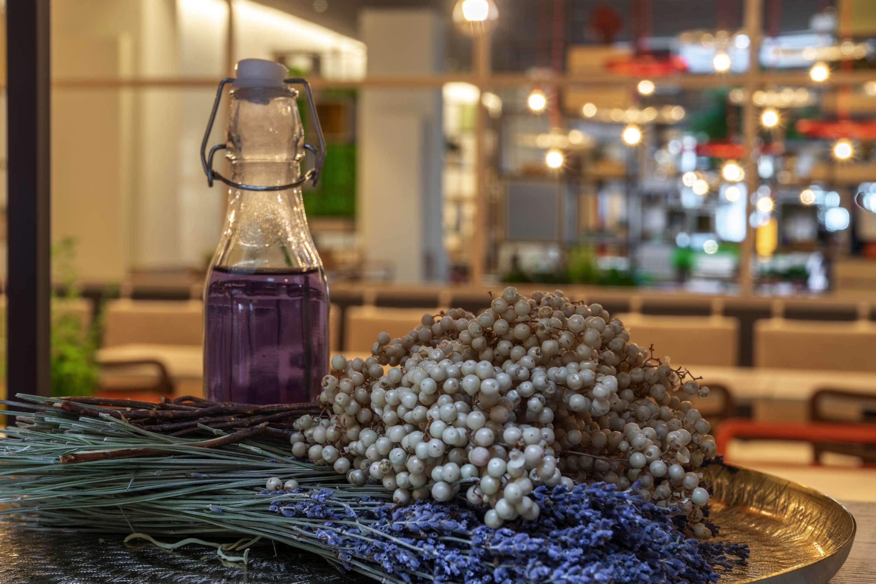 A table with a glass bottle, a pile of white grapes, and dried lavender.