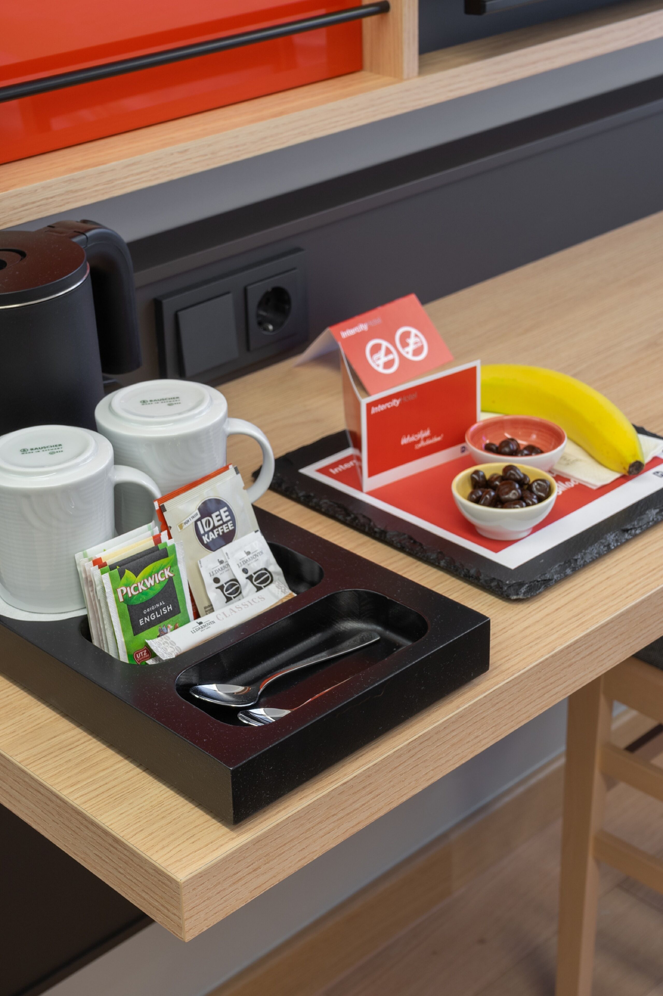 A breakfast tray with coffee packets, a banana, and a bowl of coffee on a wooden table.