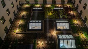 A rooftop garden with multiple seating areas and pathways, surrounded by a building with uniform windows. - IntercityHotel Budapest (Budapest)