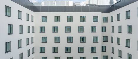 Un bâtiment moderne doté d’une cour intérieure aménagée avec des espaces verts et des panneaux solaires.